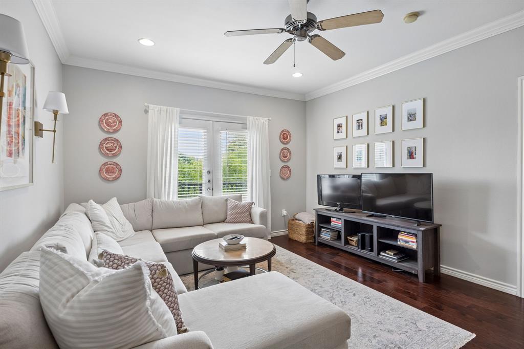 Living area featuring rich wood-finish flooring, light gray wall tones, and white crown molding