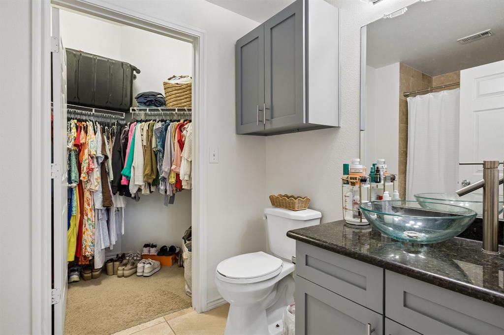 Bathroom featuring a dark stone countertop, a clear vessel sink, and a modern chrome faucet
