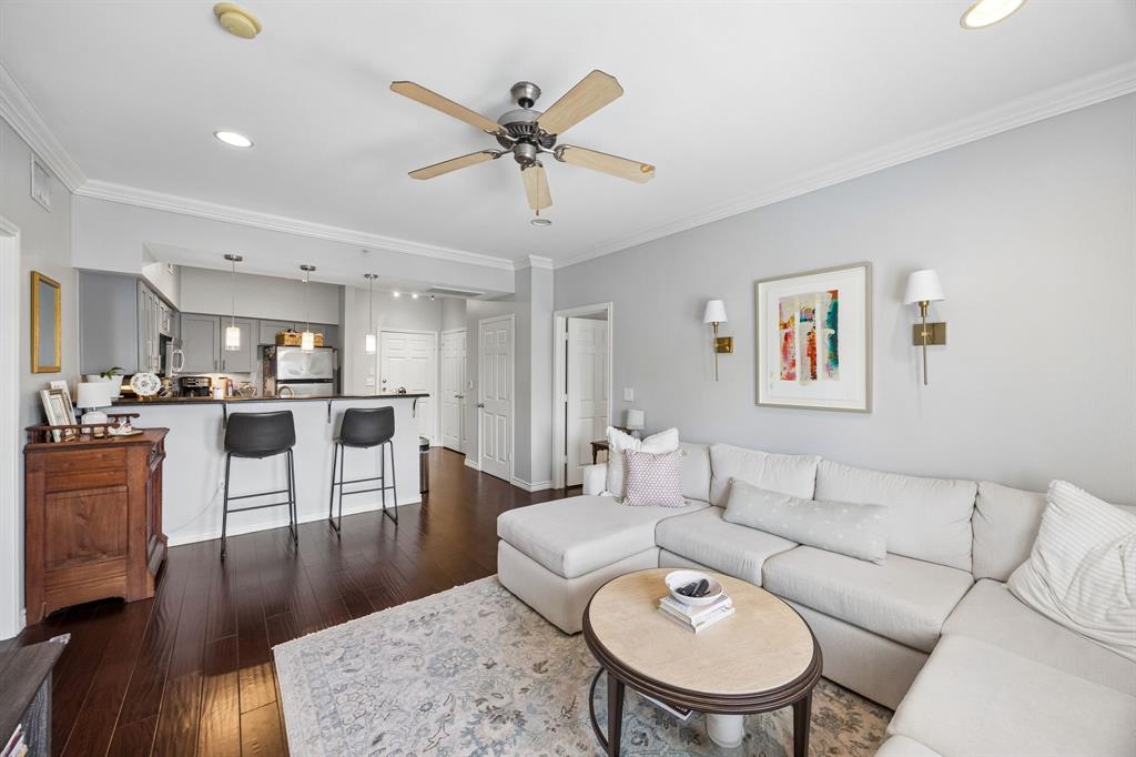 Open-concept living space featuring wood-finish flooring, recessed lighting, and crown molding