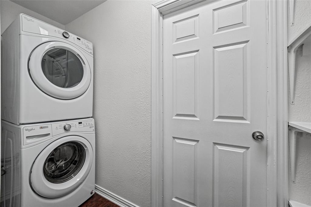 Stacked washer and dryer unit, six-panel interior door, and wall-mounted shelving
