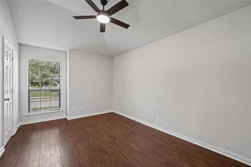 Vaulted ceiling featuring a dark-finish ceiling fan with integrated lighting, wood-finish flooring, and a single-pane window