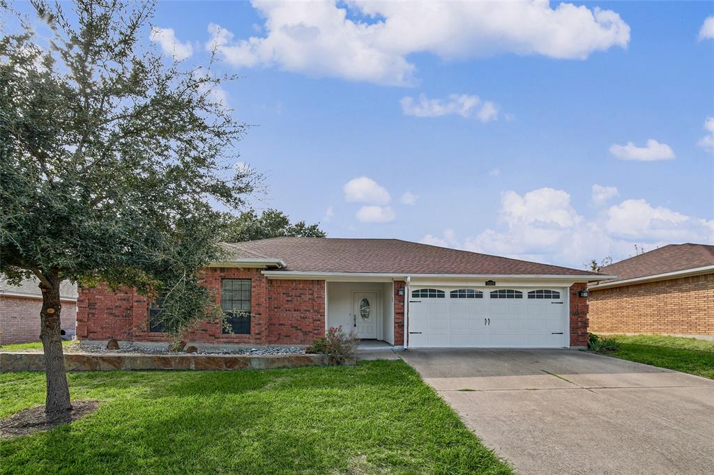 Single-story brick exterior featuring an attached two-car garage, covered entryway, and stone-bordered front garden
