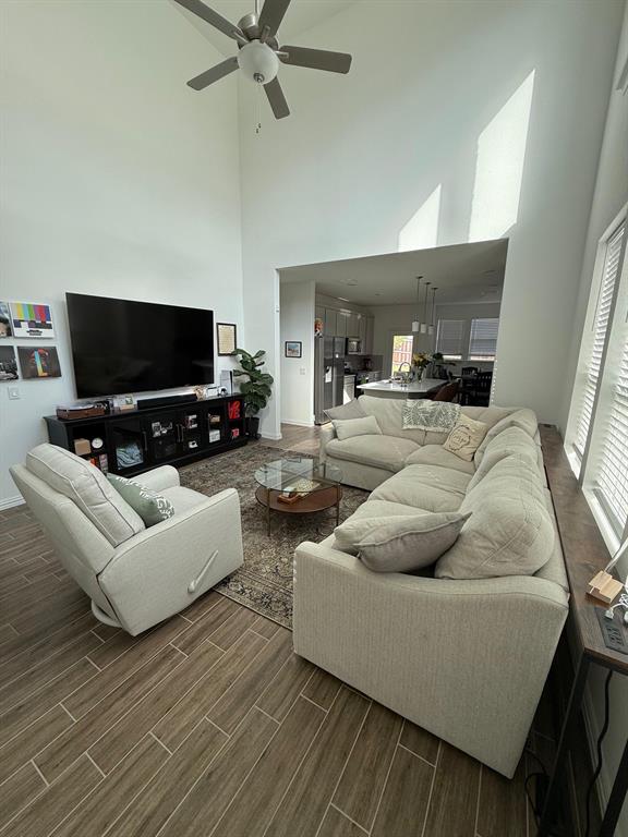 Living room featuring a towering ceiling, wood tiled floors, and a ceiling fan