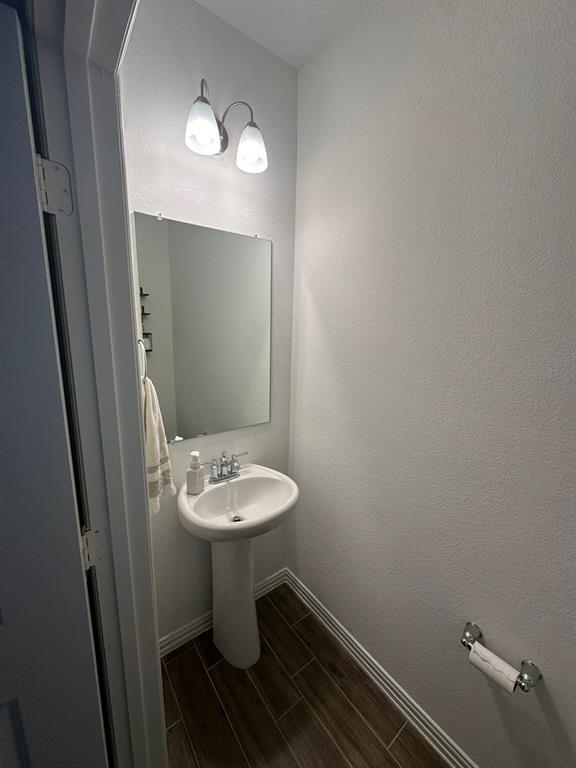 Half bathroom with wood tiled floors and a textured wall