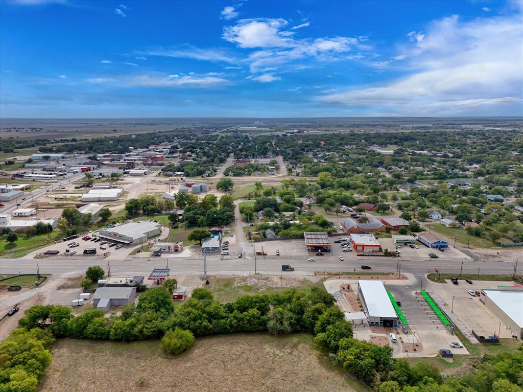 Aerial perspective of expansive open land with mature tree buffers and paved road frontage
