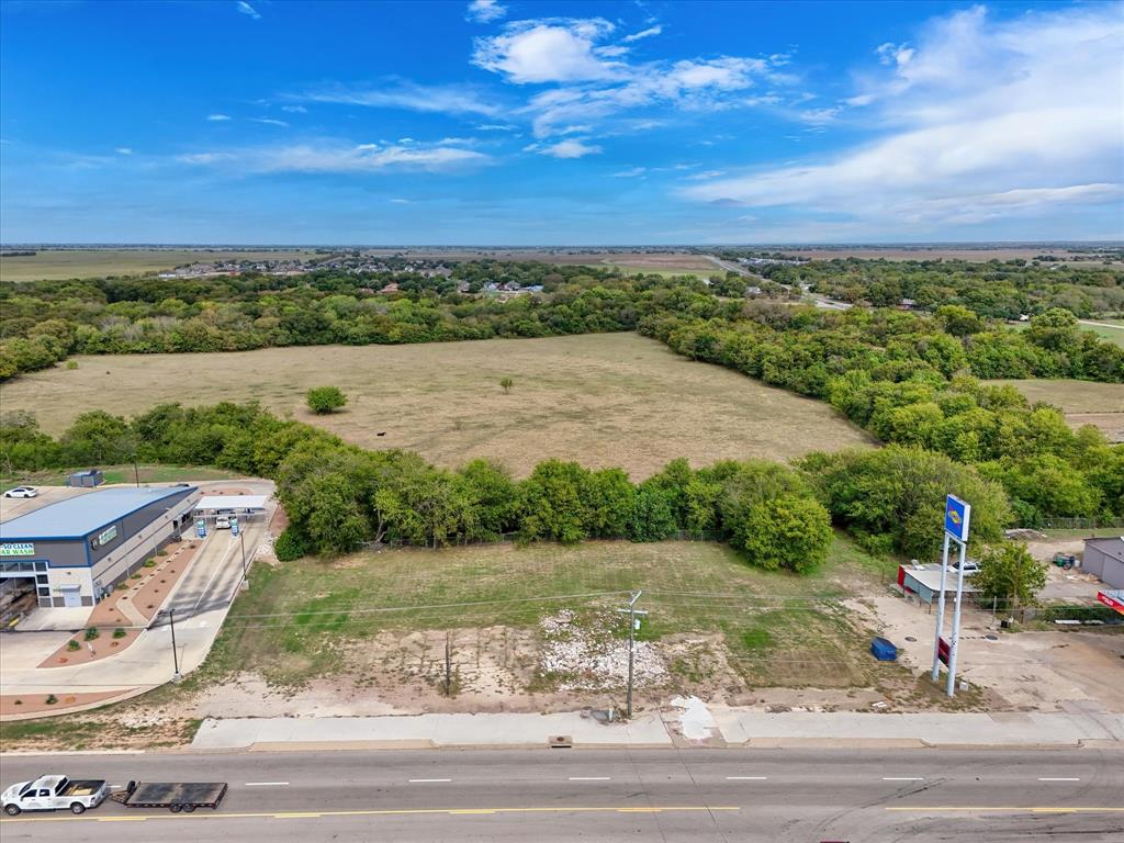 Expansive vacant lot featuring frontage on a paved thoroughfare, level terrain, and a line of mature trees