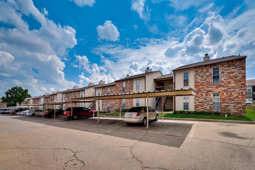 Exterior façade featuring multi-toned masonry and siding, metal-roofed covered parking, and concrete paving Exterior façade featuring multi-toned masonry and siding, metal-roofed covered parking, and concrete paving