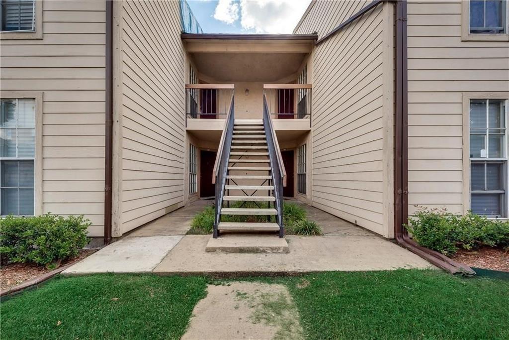 Two-story exterior featuring horizontal lap siding, a central metal staircase with railing, concrete walkway, and multi-pane windows Two-story exterior featuring horizontal lap siding, a central metal staircase with railing, concrete walkway, and multi-pane windows