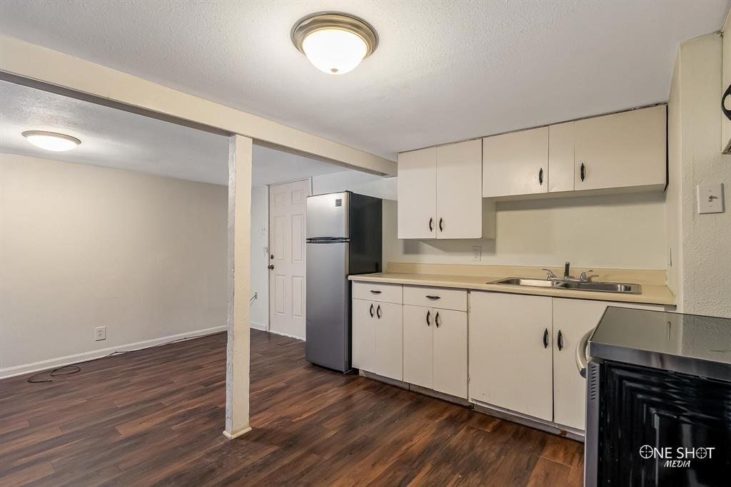 Kitchen with stainless steel fridge, dark hardwood / wood-style flooring, a textured ceiling, and sink