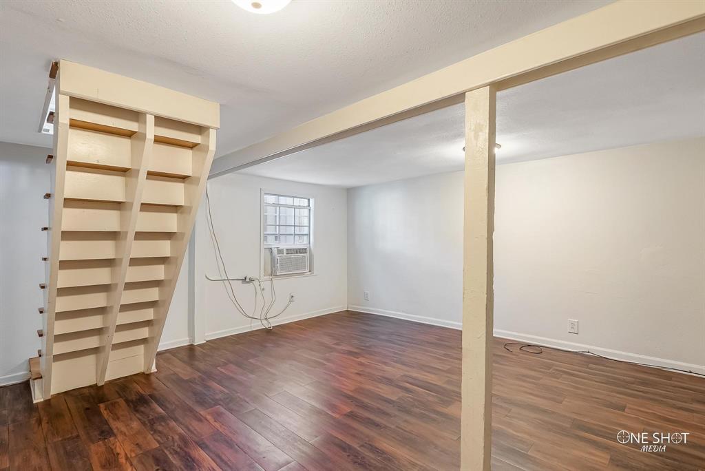 Basement with a textured ceiling, cooling unit, and dark wood-type flooring