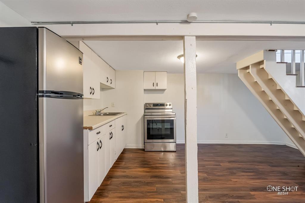 Kitchen featuring appliances with stainless steel finishes, dark hardwood / wood-style floors, white cabinetry, and sink