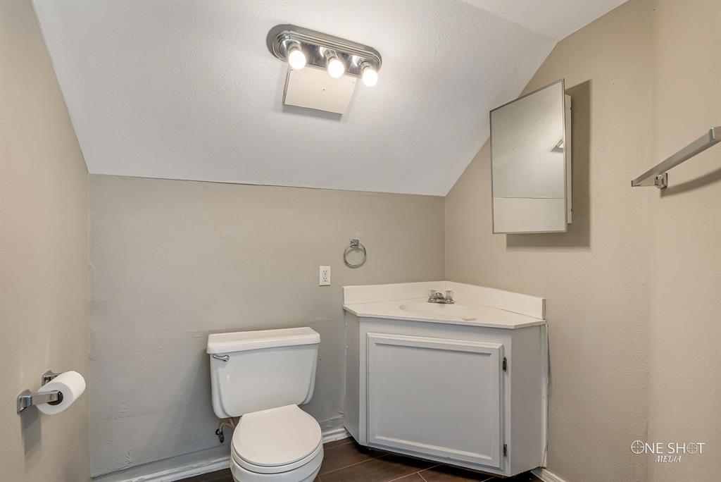 Bathroom featuring vanity, vaulted ceiling, and toilet
