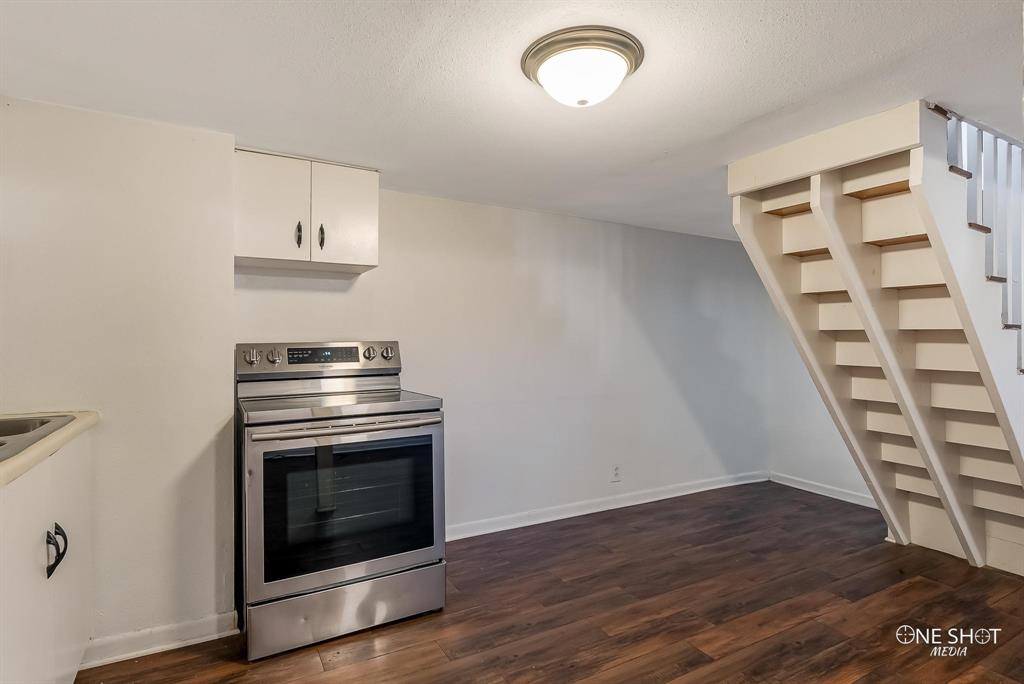 Kitchen featuring a textured ceiling, dark hardwood / wood-style floors, white cabinetry, and stainless steel electric stove