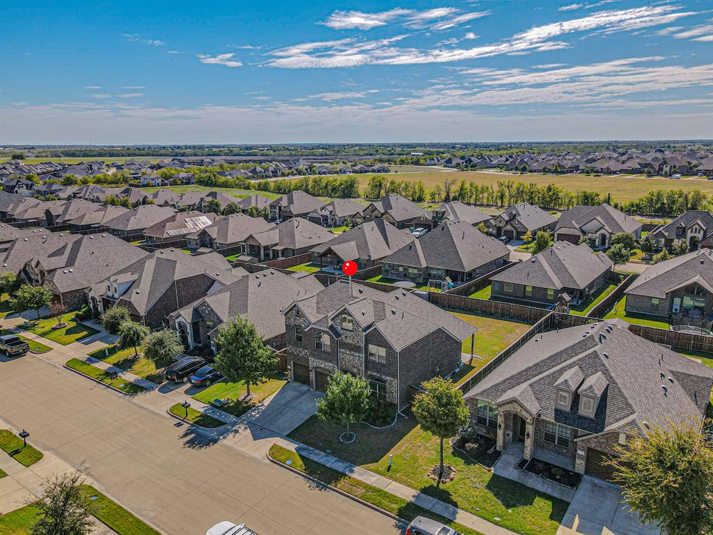 Two-story brick and stone facade, attached multi-car garage, concrete driveway, and landscaped front lawn