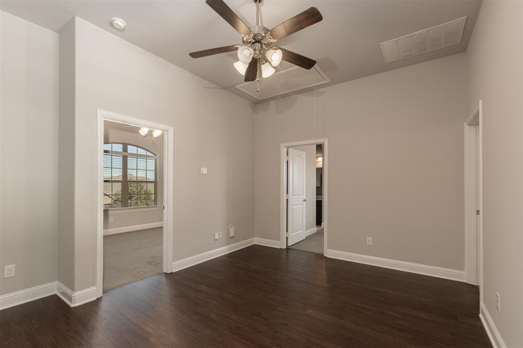 High-ceilinged room featuring dark wood-finish flooring, a multi-light ceiling fan, and arched window details