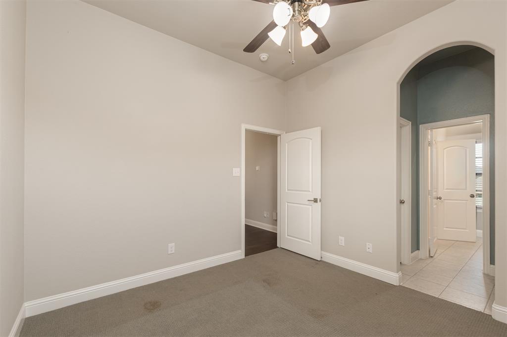 Room featuring high ceilings, a central ceiling fan with multi-light fixture, arched doorway, and solid-core paneled interior doors