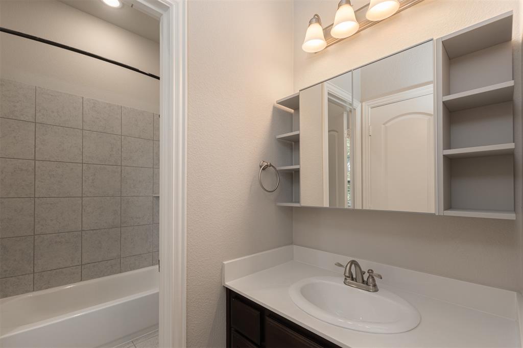 Bathroom featuring a vanity with a white countertop, inset sink, and integrated mirrored cabinetry with side shelving