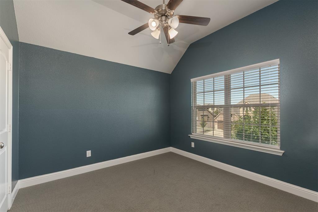 Vaulted ceiling with an integrated ceiling fan, neutral carpeting, and a large multi-pane window with horizontal blinds