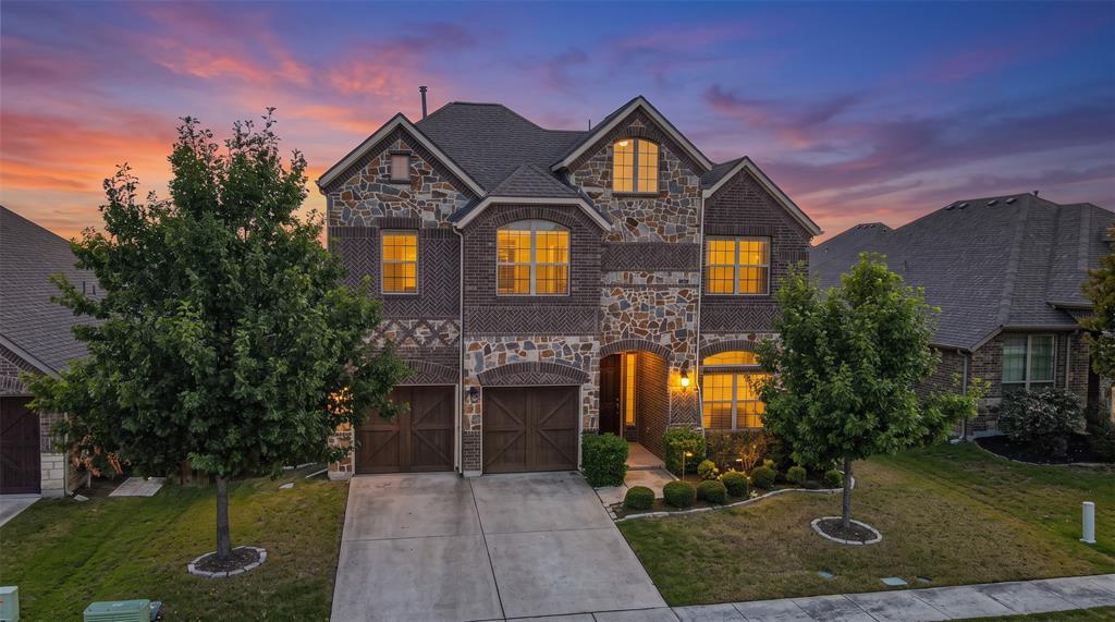 Multi-story residence featuring a stone and brick facade, dual-car garage with carriage-style doors, and an arched entryway