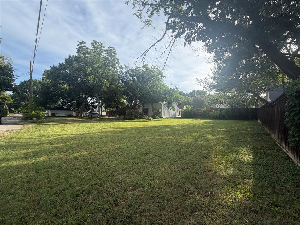 Expansive lot featuring mature trees, partial wood fencing, and open green space