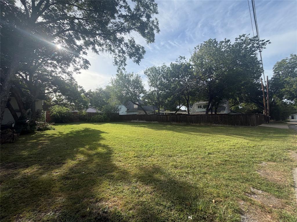 Expansive lot featuring mature trees, level topography, and perimeter wood fencing