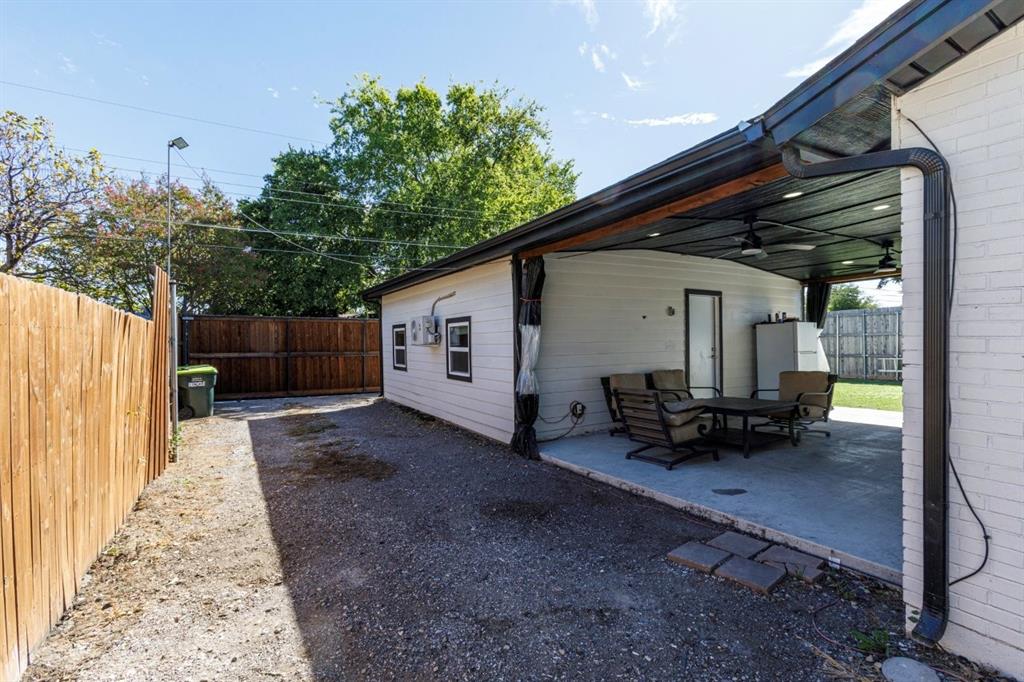 Covered patio with recessed lighting and ceiling fans, white-painted brick exterior, and wood-panel privacy fencing