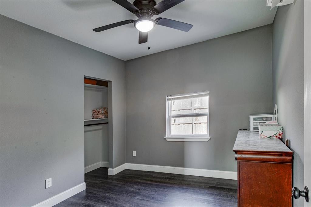 Room featuring dark wood-finish flooring, a neutral wall palette, a built-in reach-in closet, a ceiling fan with integrated lighting, and a window with a horizontal blind