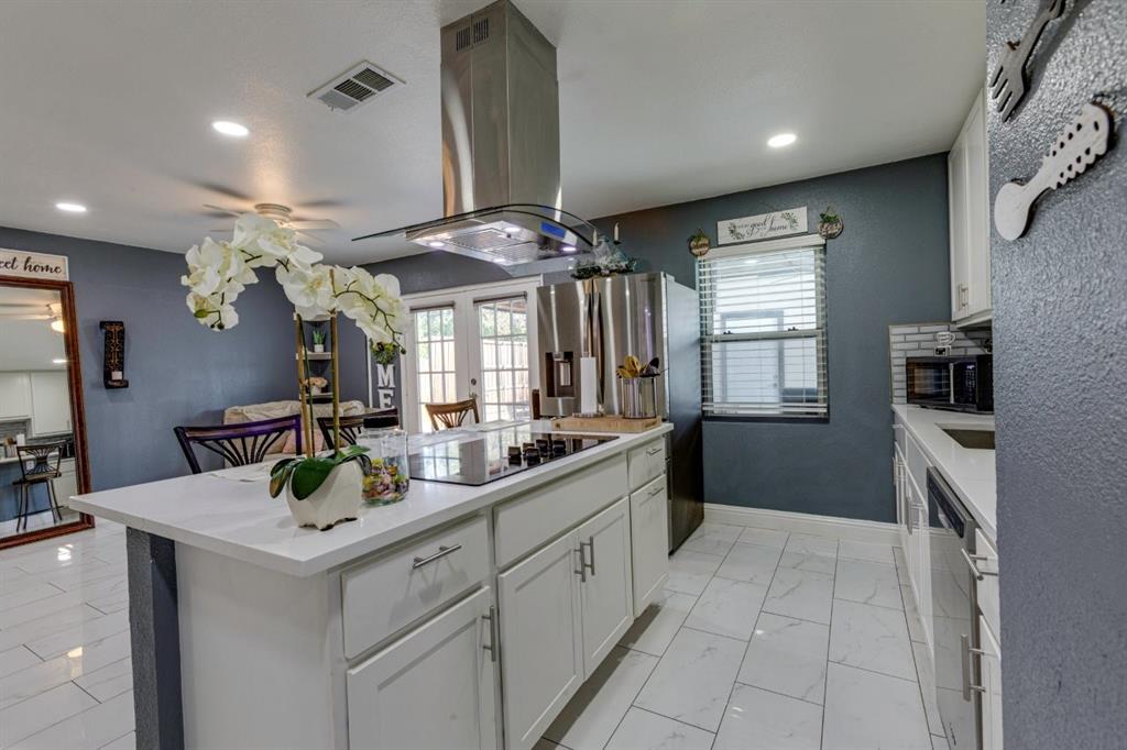 Kitchen featuring an island with a smooth-surface cooktop, stainless steel chimney-style range hood, white shaker-style cabinetry, and polished tile flooring