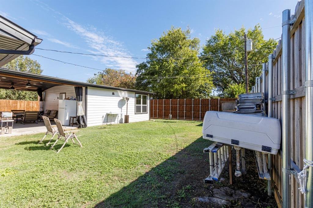 Backyard featuring a concrete patio, wood privacy fencing, and a covered outdoor area