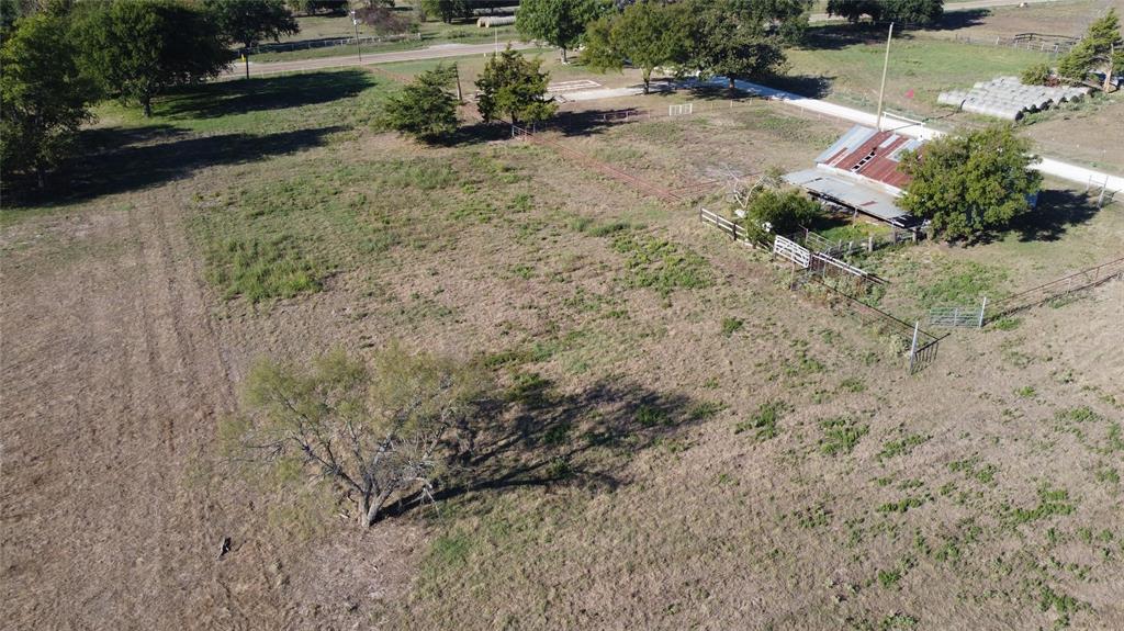 Expansive acreage featuring mature trees, perimeter fencing, and a metal-roofed structure