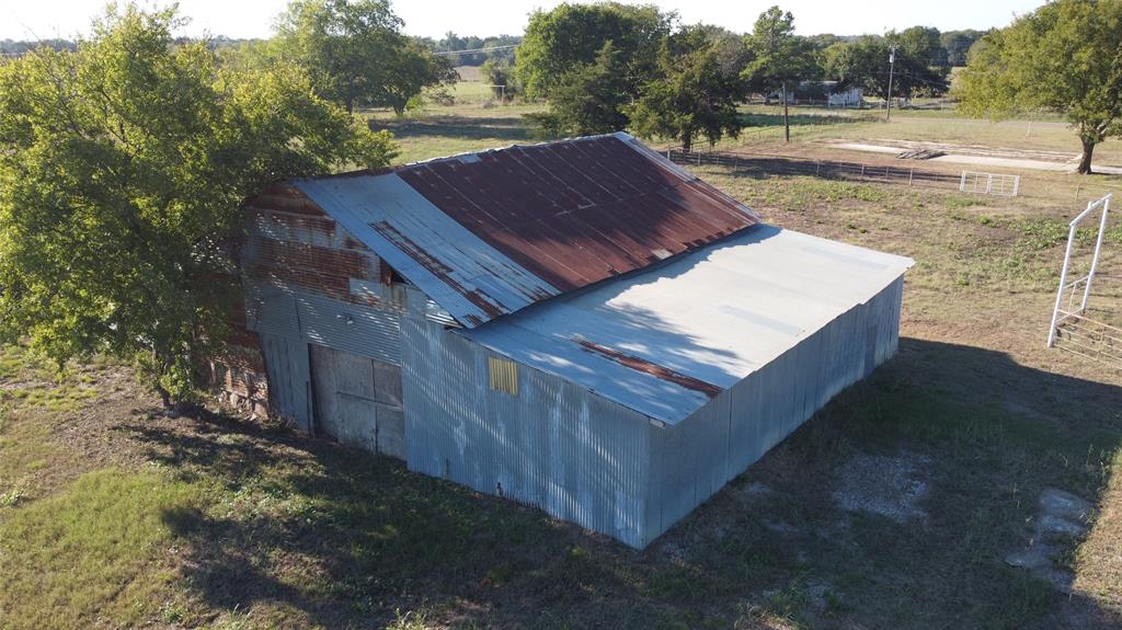Outbuilding with corrugated metal siding, metal roof, and sliding entrance doors, situated on cleared acreage