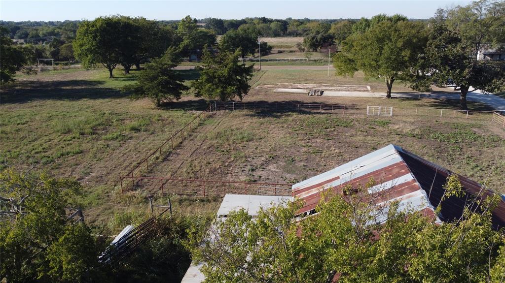 Expansive acreage featuring mature trees, perimeter wire fencing, and a metal-roof structure