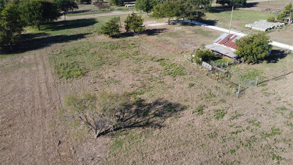Expansive acreage featuring mature trees, perimeter fencing, and an existing structure with a metal roof