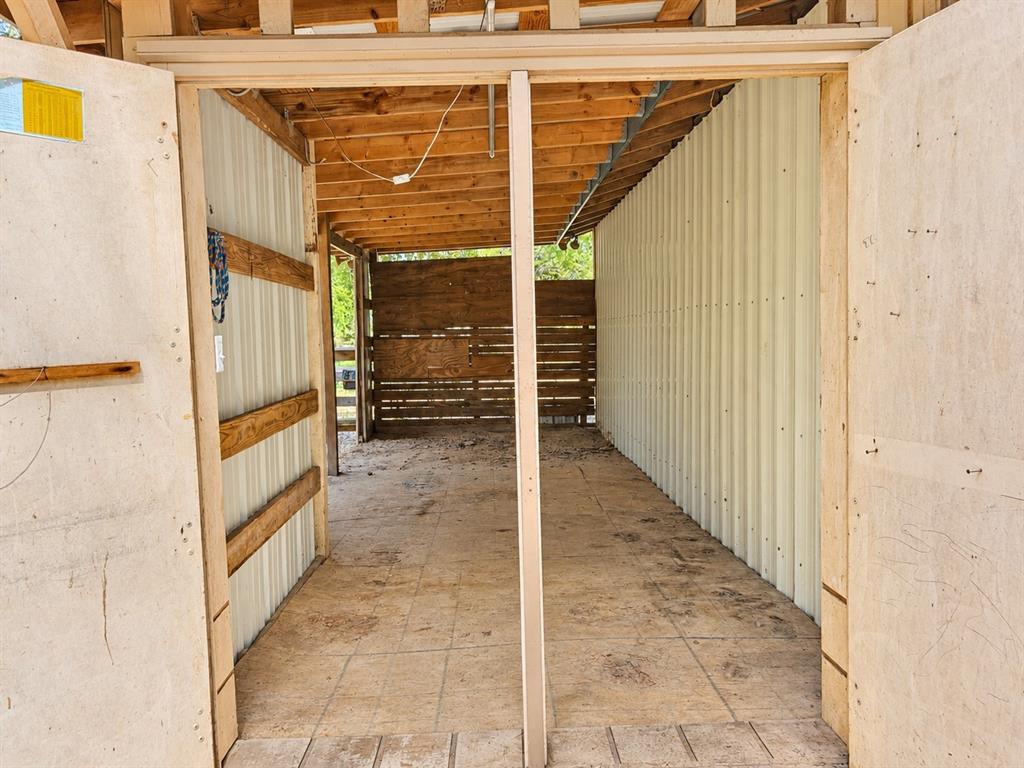 Covered exterior structure featuring corrugated metal siding, exposed timber framing, plywood flooring, and horizontal wood-slat wall panels