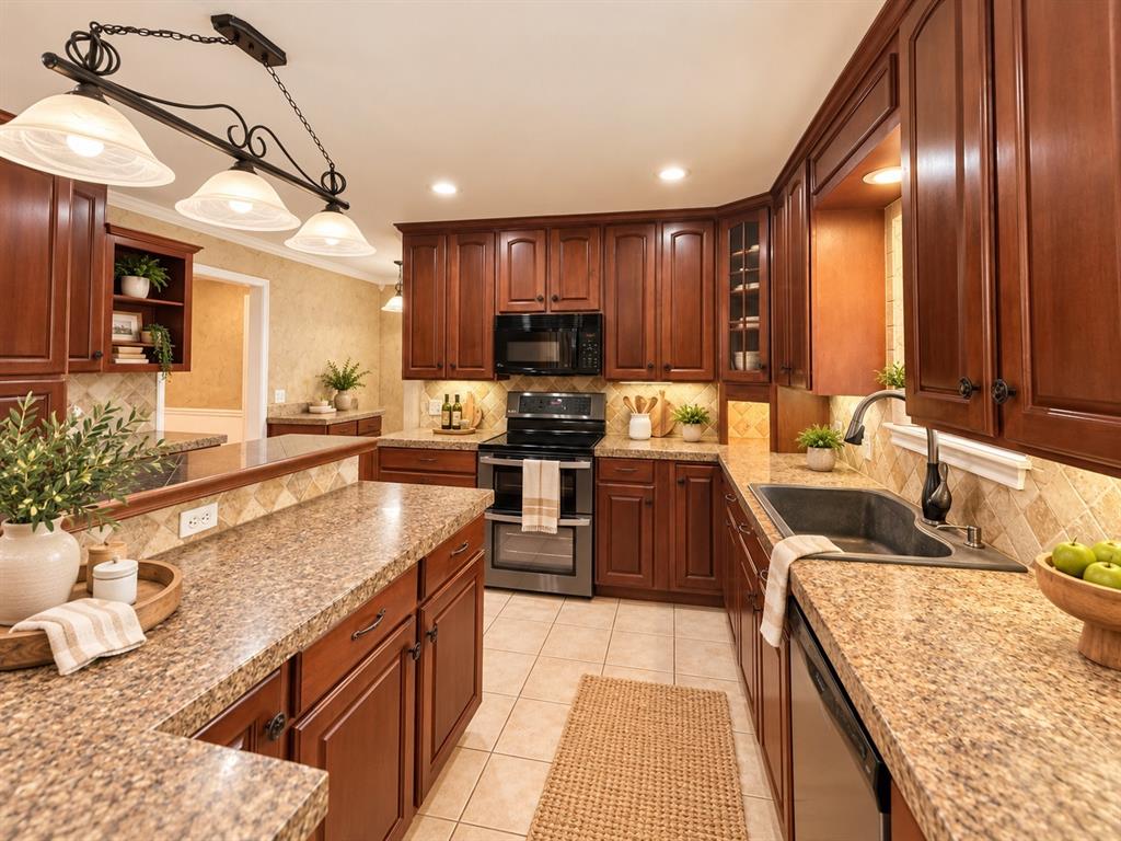 Kitchen featuring dark wood cabinetry, speckled stone countertops, tile backsplash, built-in stainless steel appliances, and a three-light pendant fixture Kitchen featuring dark wood cabinetry, speckled stone countertops, tile backsplash, built-in stainless steel appliances, and a three-light pendant fixture