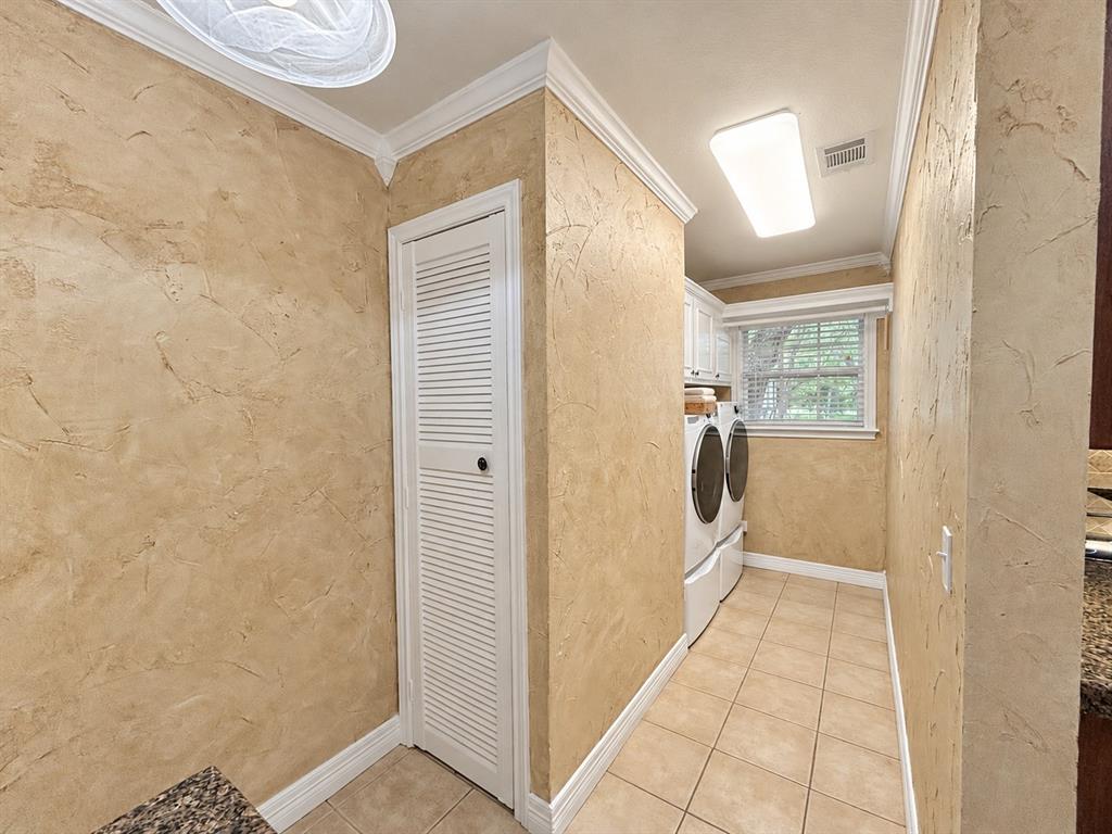 Textured wall finishes, ceramic tile flooring, louvered-style built-in cabinetry, and crown molding