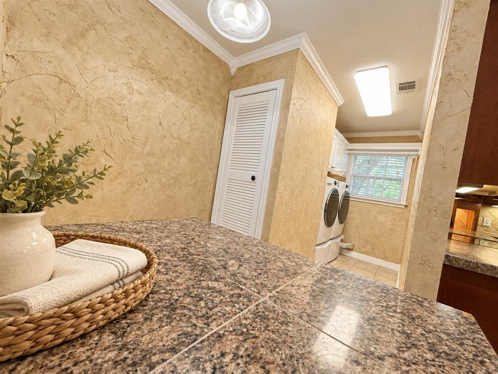 Tiled countertop, textured wall finish, louvered-panel door, and crown molding