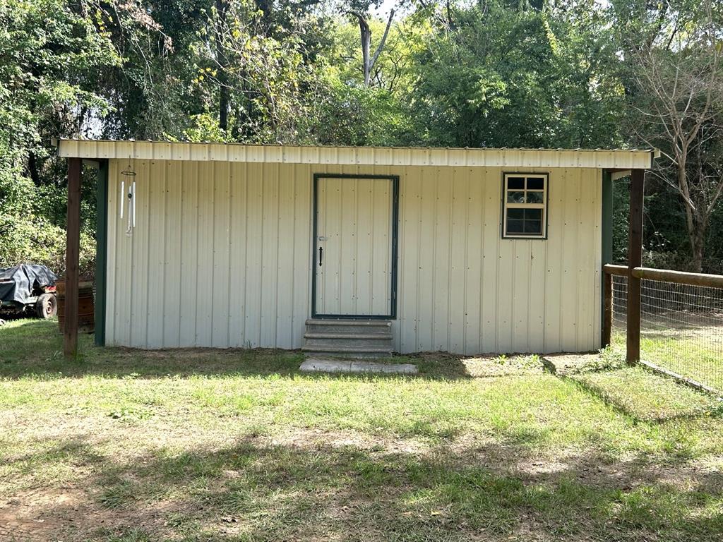 Detached exterior structure featuring metal siding, a single-pane grid window, a central entry door, and concrete step