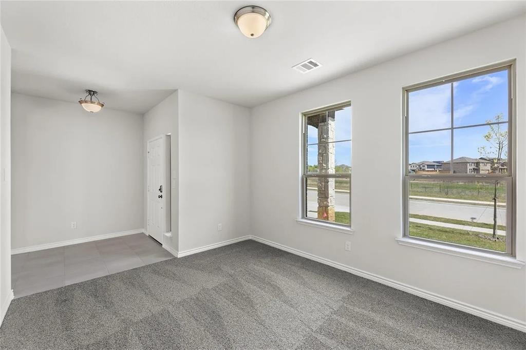 Interior space featuring neutral wall paint, carpeted flooring, large grid-pattern windows, and two flush-mount light fixtures