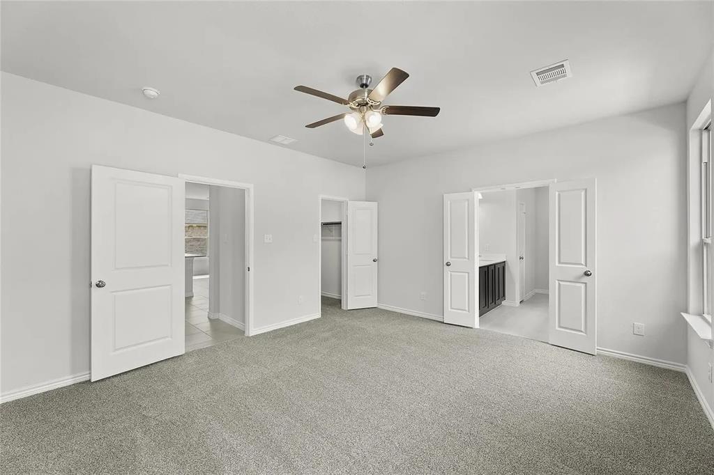 Neutral-toned carpeting, ceiling-mounted light fixture with fan, and multi-panel interior doors