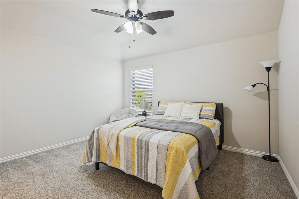 Neutral wall color, wall-to-wall carpeting, window with slatted blinds, and ceiling fan with integrated lighting