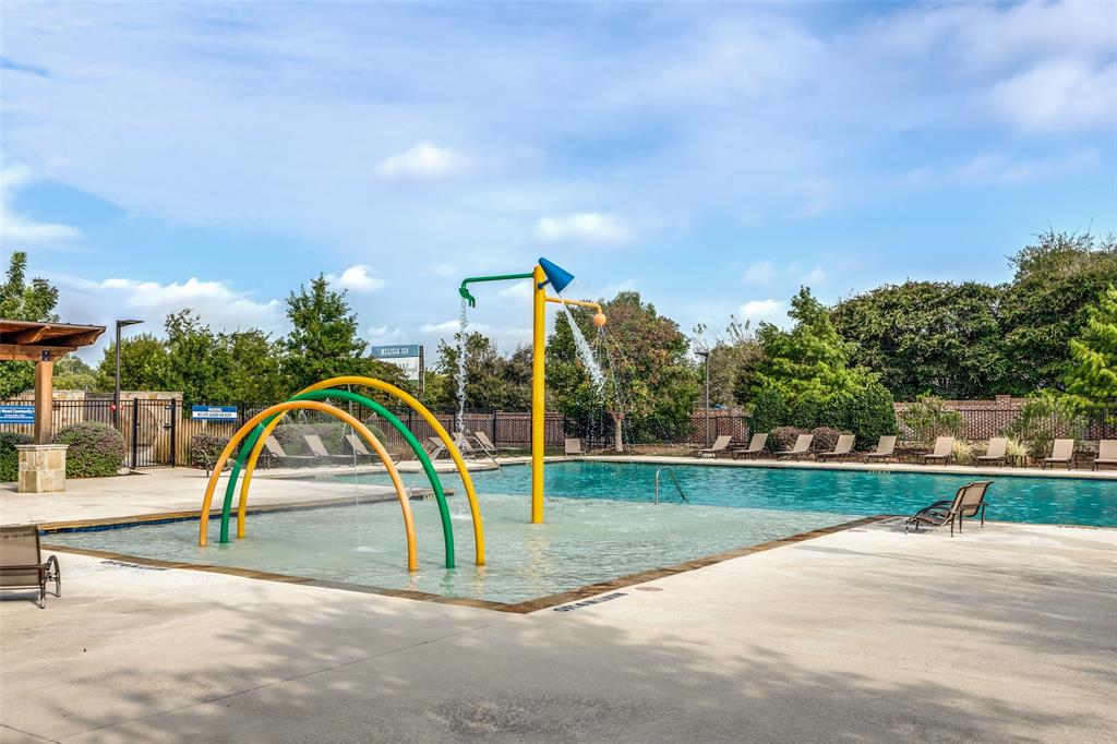 Swimming pool featuring a zero-entry area, water spray arches, overhead water feature, and expansive concrete decking