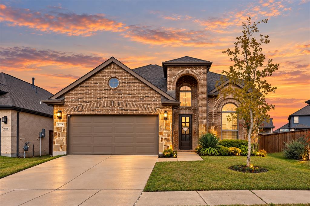 Brick exterior featuring an arched entryway, decorative stone masonry accents, a circular gable window, and a multi-car garage