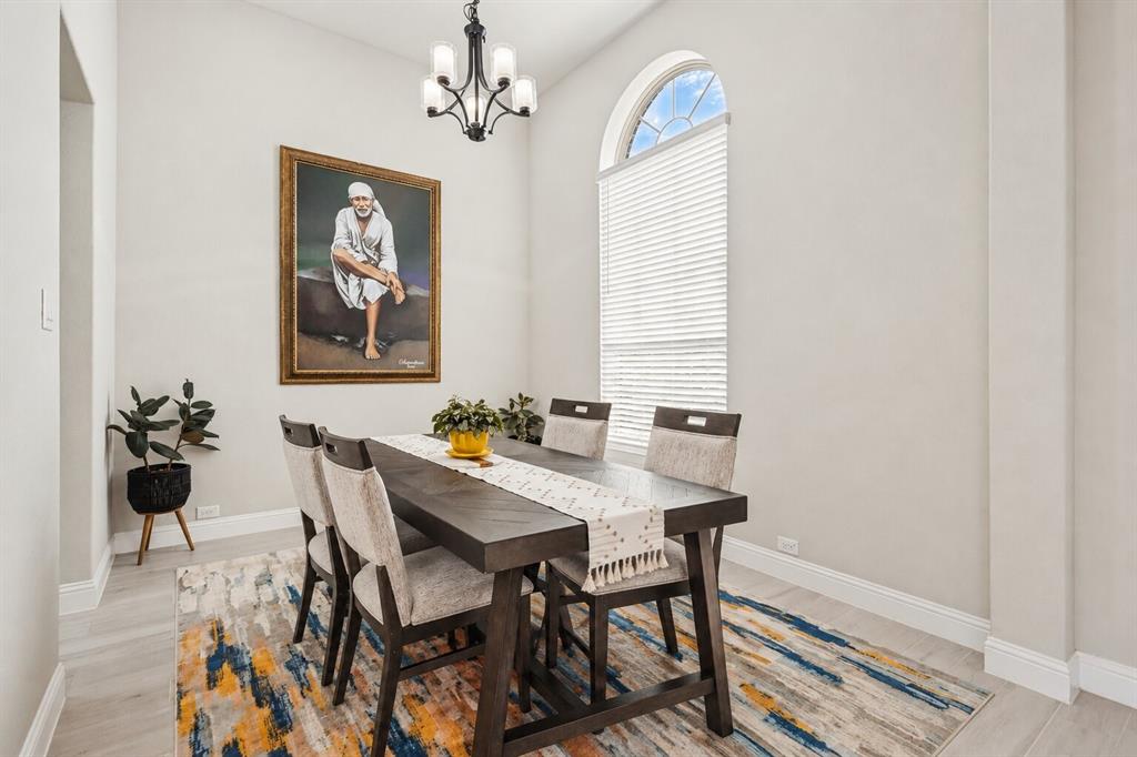 High ceilings featuring an arched window, wood-finish flooring, and a decorative chandelier