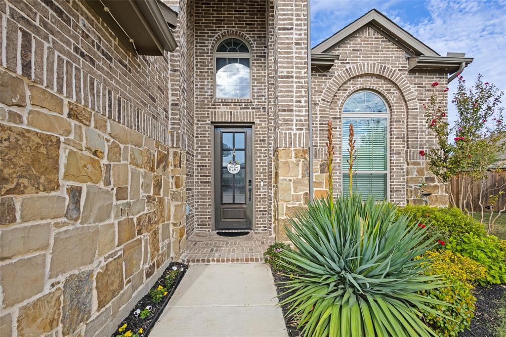 Exterior facade featuring multi-textured brick and stone masonry, arched window detailing, and a glass-paneled entry door
