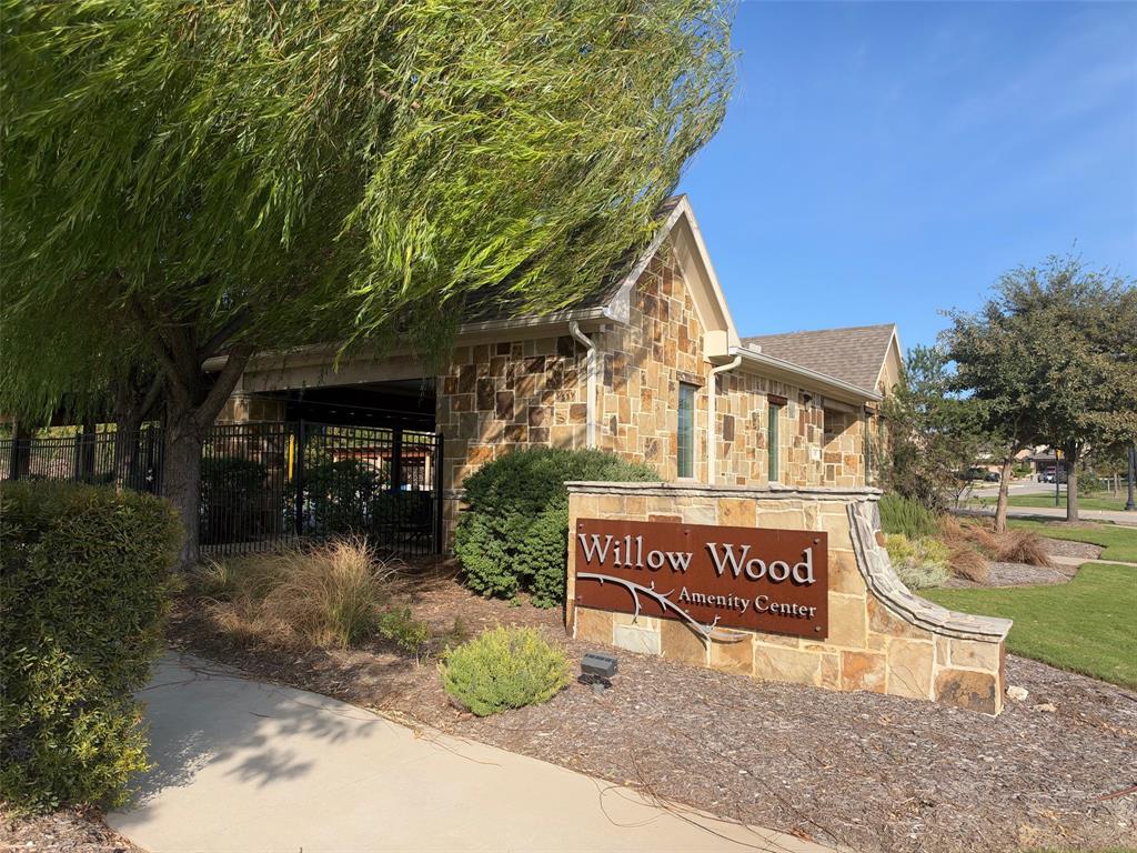 Stone-veneer amenity center featuring a covered pavilion, paved walkway, and landscaping
