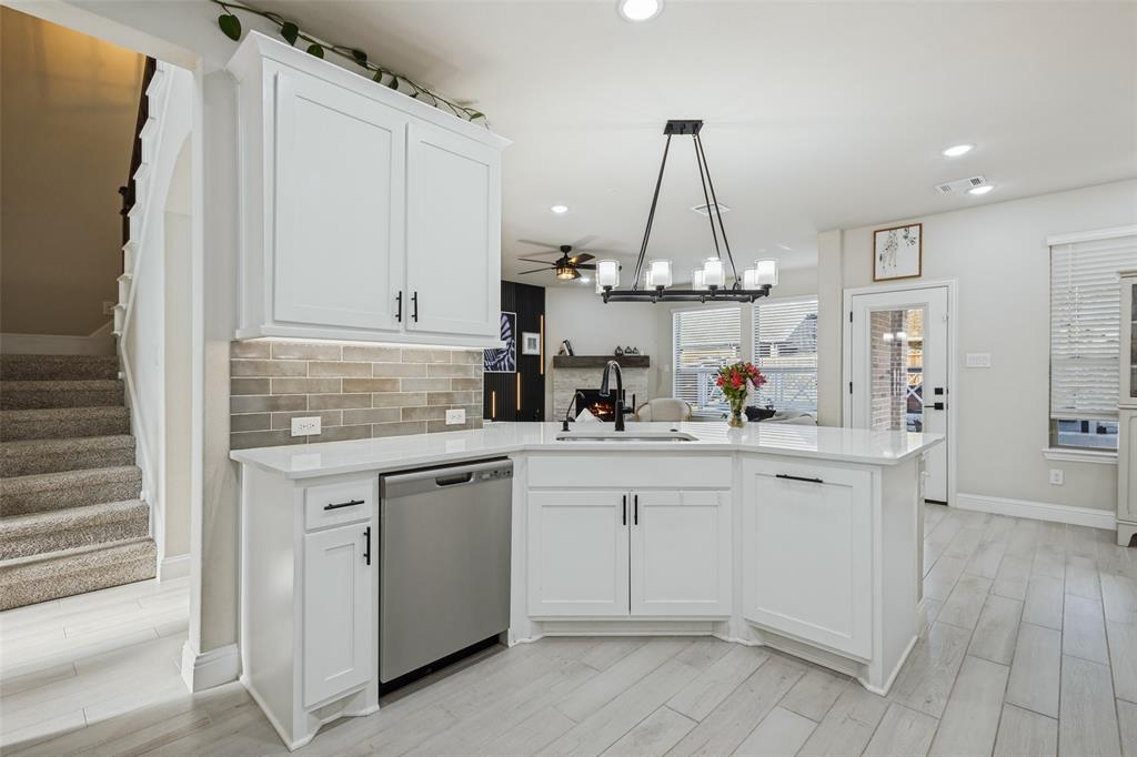 Kitchen featuring white shaker-style cabinetry, white countertops, a tiled backsplash, wood-finish flooring, and a multi-light chandelier