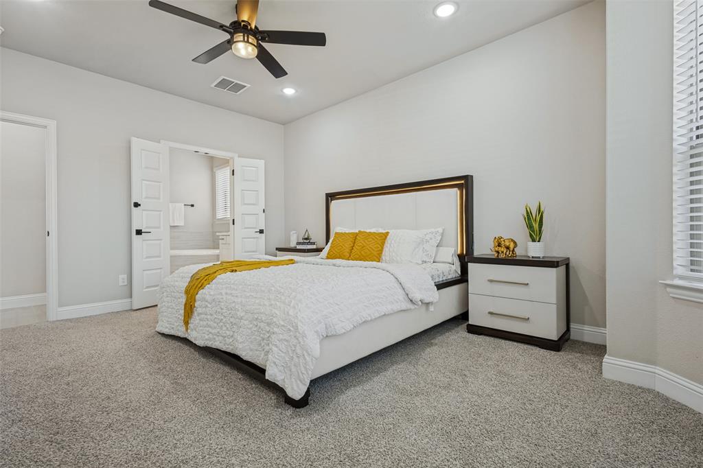 Neutral-toned carpeted interior featuring recessed lighting, a modern ceiling fan with integrated lighting, and white multi-panel double doors