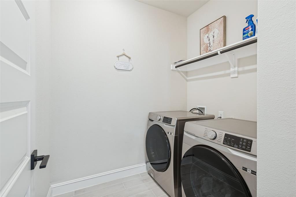 Utility room featuring large-format tile flooring, built-in shelving, and a mounted hanging rod