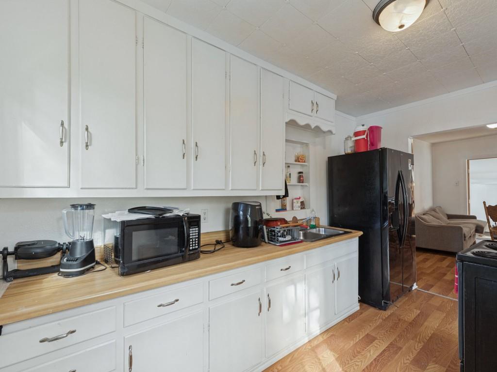 Kitchen featuring white cabinetry, light wood-finish countertops, built-in shelving, wood-finish flooring, and a flush-mount light fixture